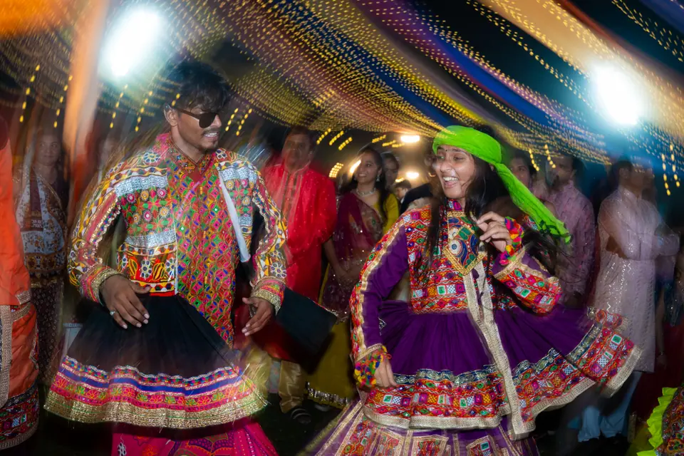 Two khelaiyas in mirror-work outfits dancing face to face under the canopy lights