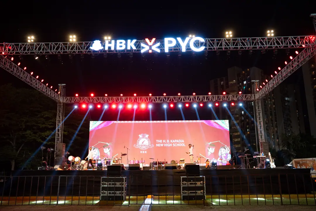The PYC stage at night, HBK ✕ PYC lit up along the truss and the school’s name on the LED wall